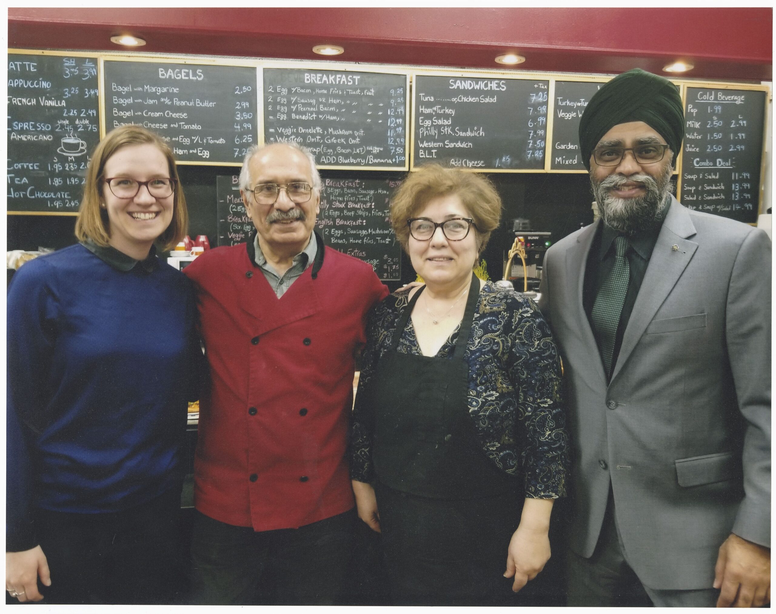 four people standing in front of the coffee shop menu