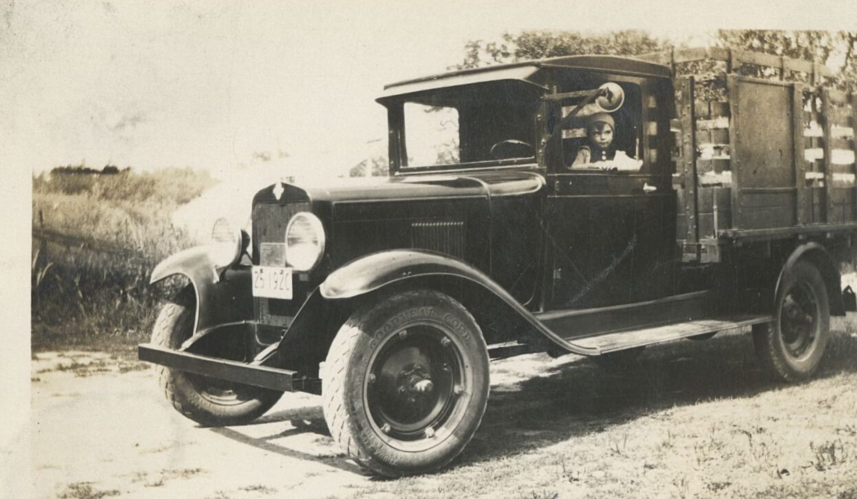 a black-and-white photo of a child in an old-fashioned pickup truck
